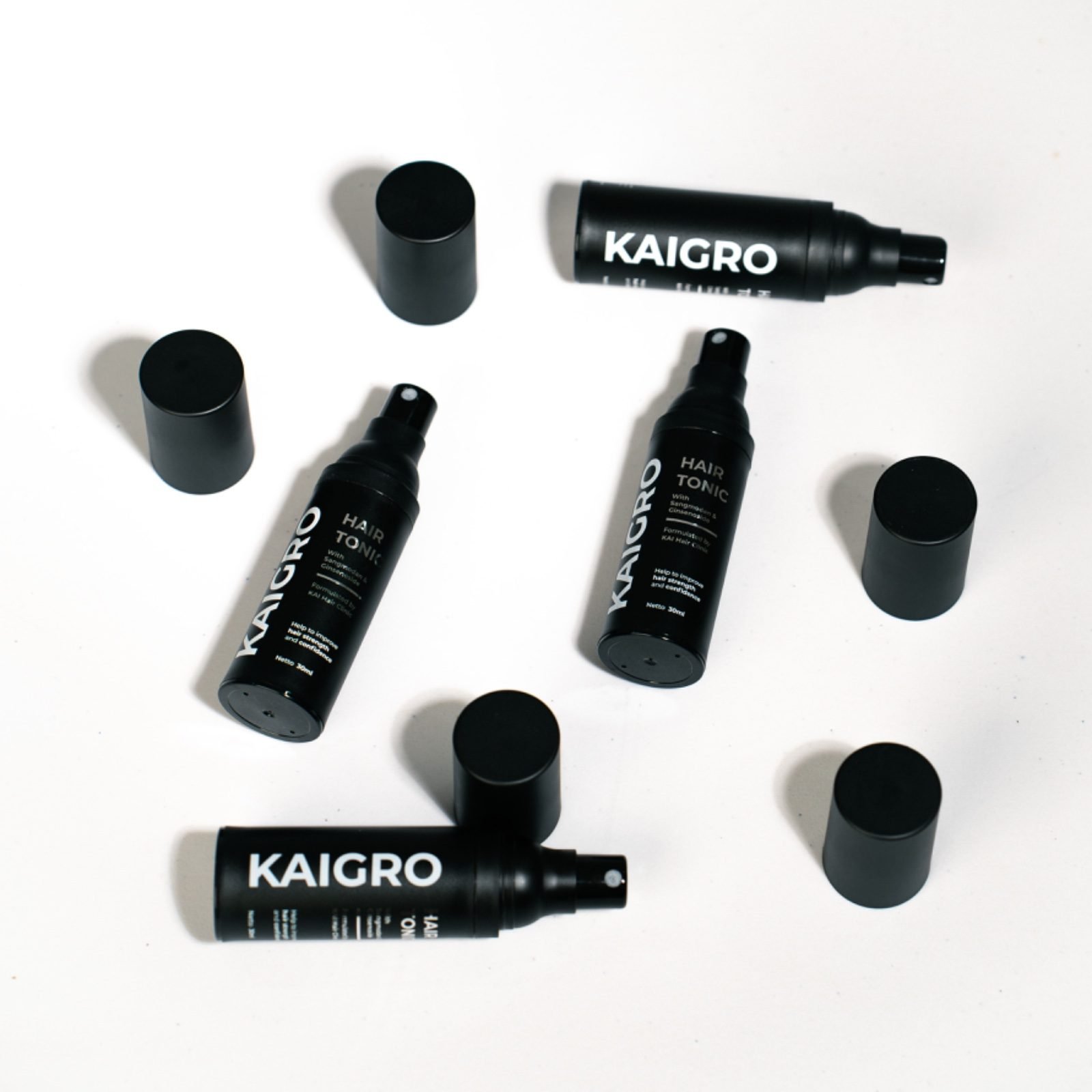 Beberapa botol hair tonic KAIGRO hitam dengan tutup terbuka di atas latar putih