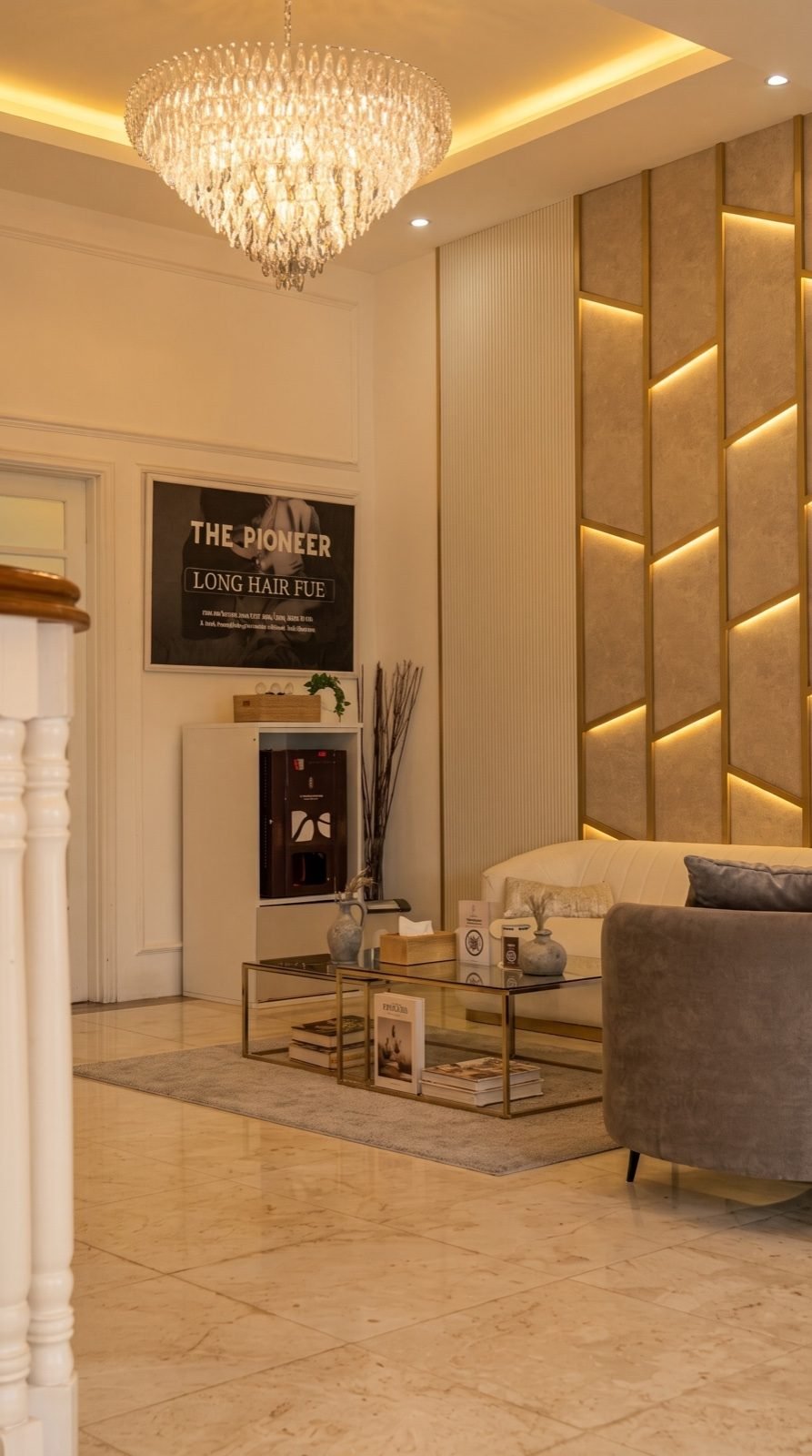 Lobi KAI dengan lampu kristal, dinding panel berlis emas, sofa krem, dan poster The Pioneer Long Hair FUE